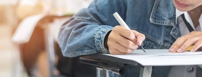 exam with school student having a educational test, thinking hard, writing answer in classroom for  university education admission and world literacy day concept