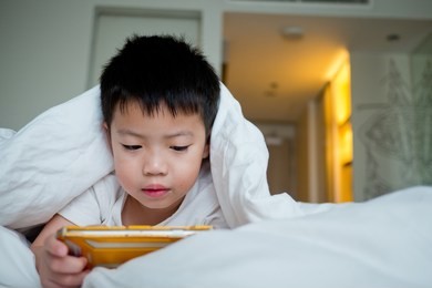 asian chinese boy playing smartphone on bed, watching smartphone, kid use phone and play game, child use mobile, addicted game and cartoon
