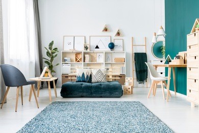 patterned carpet near armchair and emerald mattress in colorful living room interior with chair at desk