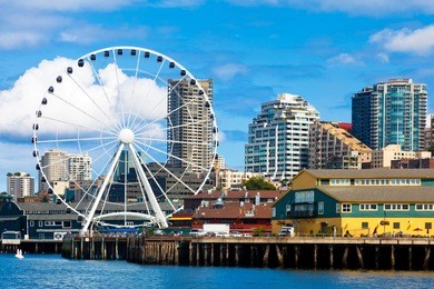 seattle ferris wheel, waterfront and skyline on a bright sunny day with blue sky and clouds.  view is from the water.  close up