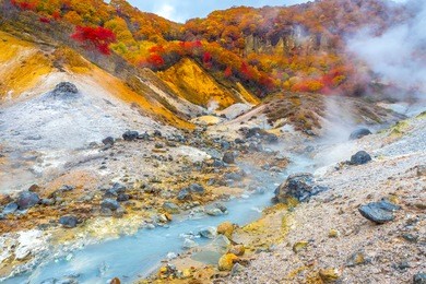 jigokudani hell valley in hokkaido, japan. hell valley in japanese is 'noboribetsu'. it is one of the famous tourist destination to visit. white heavy sulfur gas steaming from the ground smell bad.