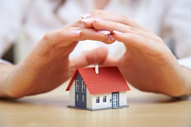 female hands saving small house with a roof