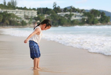 exciting asian child girl while come to play sand and sea at the beach on holiday.