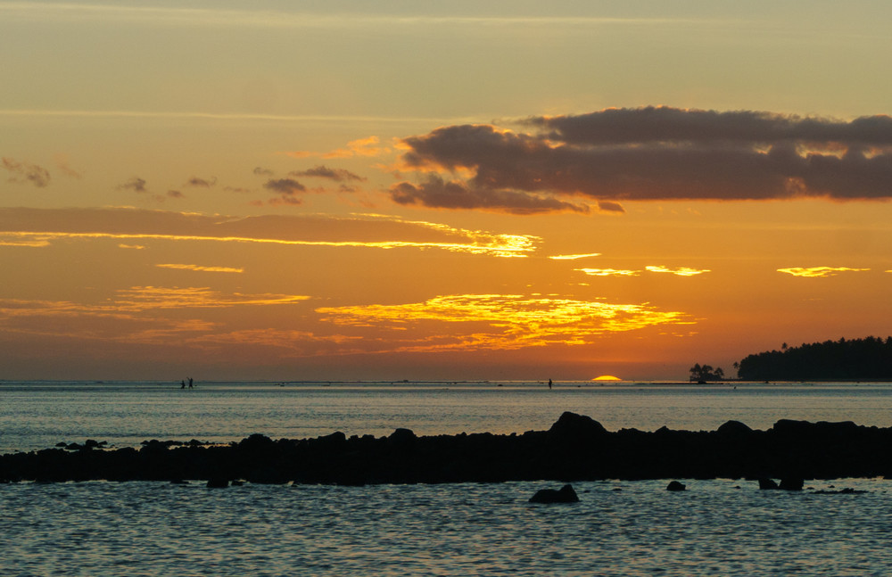 fijian sunset. locals in the ocean during low tide, southern coast of viti levu, fiji.