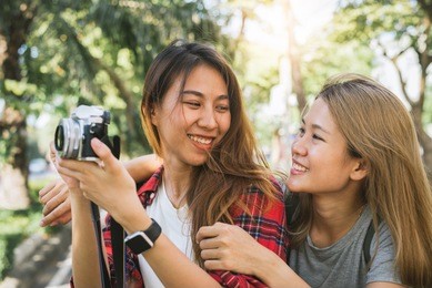 happy beautiful traveler asian friend women carry backpack. young joyful friend asian women using camera to making photo during city tour, cheerful emotions. women lifestyle outdoor in city concept.