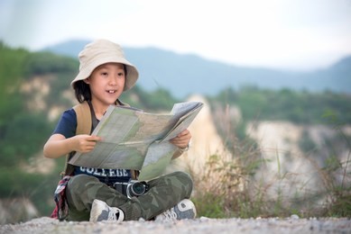 children asian girl holding maps and travel backpacks standing in the mountain. travel concept
