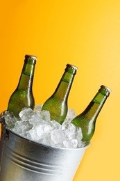 three green beer bottles in ice bucket with condensation