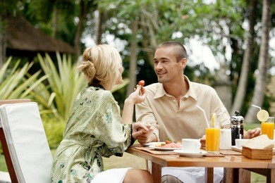 attractive couple having breakfast in an exotic garden while on vacations, smiling.