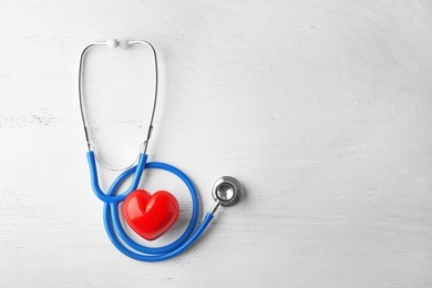 stethoscope and red heart on white wooden background. health care concept