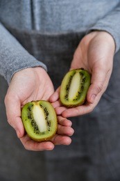 woman holds kiwi halves in hanfs close