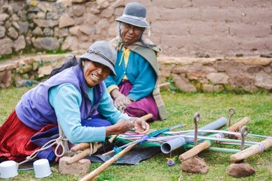 happy native american mother and daughter weaving authentic aymara cloth.