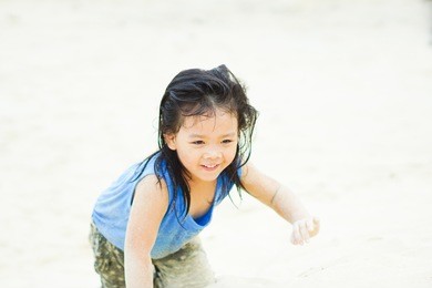 happy little asian girl playing white sand on summer beach in phuket thailand.summer vacation and relax concept.