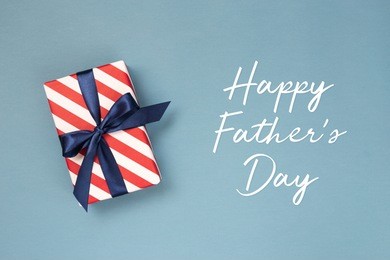 happy father's day greeting card with decorated gift box on blue background. top view.