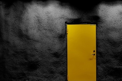                          yellow door with black wall with shadows and light. copy space.      