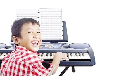 portrait of little piano player smiling and playing the piano. shot in studio isolated on white