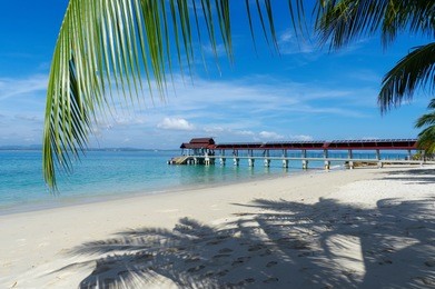 a jetty connecting an island with green sea water, beautiful scenery tropical sea view at kapas island, malaysia with white sandy beach ,rocky beach and clear water.
