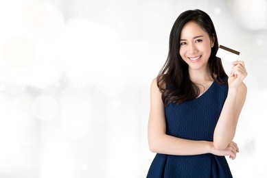 young smiling beautiful asian woman presenting credit card in hand showing trust and confidence for making payment