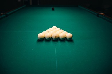 billiard table with a triangle of white cue balls on it. sports and indoor games free time concept.