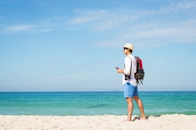 asian young traveler looking to the beach sky, enjoying the beach, summer holidays, and the concept of vacationing on holiday.summer and travel concept.