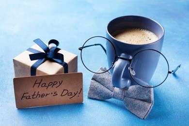 creative breakfast on happy fathers day with gift box, funny face from cup of coffee, eyeglasses and bowtie.