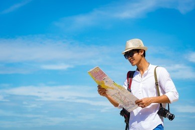 happy smiling caucasian tourist asian young asian man traveler looking maps with camera on the beach. summer and travel concept.