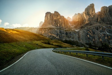 beautiful mountain road with trees, forest and mountains in the backgrounds. taken at state highway road in passo gardena, sella mountain group of dolomites mountain in italy.
