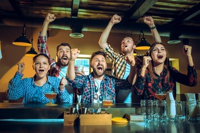 sport, people, leisure, friendship, entertainment concept - happy male and female football fans or good yuong friends drinking beer, celebrating victory at bar or pub. human positive emotions concept