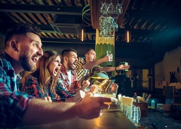 sport, people, leisure, friendship, entertainment concept - happy male and female football fans or good yuong friends drinking beer, celebrating victory at bar or pub. human positive emotions concept