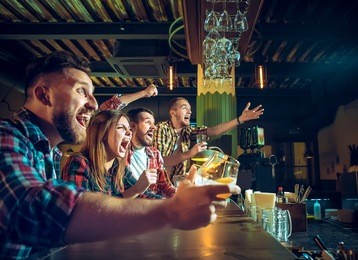 sport, people, leisure, friendship, entertainment concept - happy male and female football fans or good yuong friends drinking beer, celebrating victory at bar or pub. human positive emotions concept