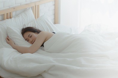 on the bed in a white room, there are women sleeping.asian girl dreams.beautiful woman lying in bed in the room.soft pillow and warm blanket make a good dream.do not focus on objects.