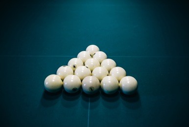 billiard table with a triangle of white cue balls on it. sports and indoor games free time concept.