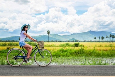 woman traveler enjoying for  view of rice field. asian lady tourist riding a bicycle and looking for view of nature on holiday.