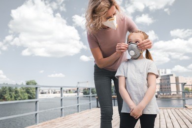 mother and daughter in protective masks on bridge, air pollution concept