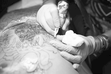 tattooist making by professional artist is tattooing body using machine in a creative design work studio. process decoration ink artwork male skin snake pattern.