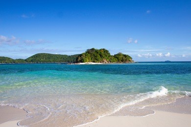 virgin beach with white sand in philippines el nido , palawan island , turquoise water blue sky wide angle shot during the day .