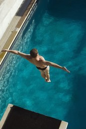 high angle view of a male diver jumping from springboard into the pool