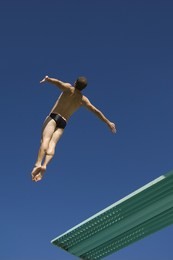 low angle view of a male diver diving from springboard in midair