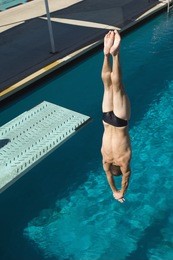 caucasian male diver diving upside down into the pool