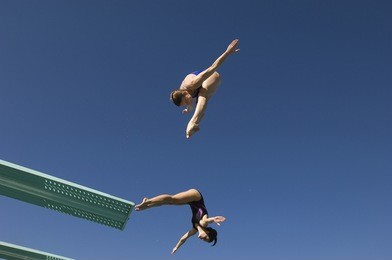 low angle view of two female divers diving in midair against clear sky