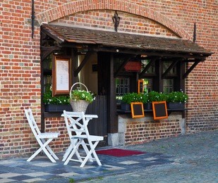 street cafe in the ancient european city. two white chairs and table stand near an entrance in cafe