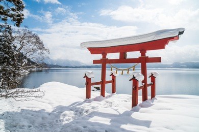 a red japanese torii in front of lake tazawa, akita prefecture, japan