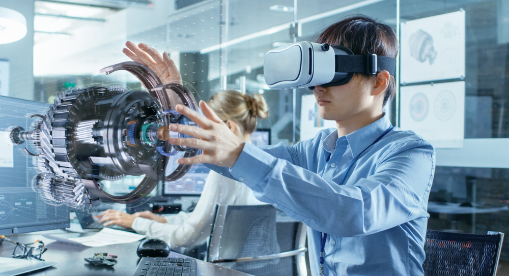 computer science engineer wearing virtual reality headset works with 3d model hologram visualization, makes gestures. in the background engineering bureau with busy coworkers.