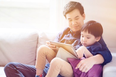 asian boy is watching a tablet. father taught social learning from around the world to his son. or what the children do not understand. it is a good family relationship. father's day family concept