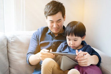 asian boy is watching a tablet. father taught social learning from around the world to his son. or what the children do not understand. it is a good family relationship. father's day family concept