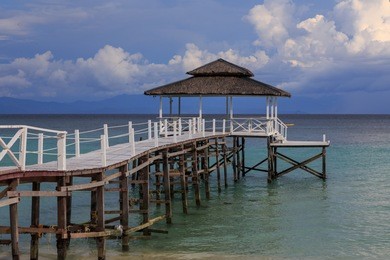 beautiful scenery landscape view of long wooden jetty and white sand beach with blue sky ocean and green ocean in mantanani island, north borneo