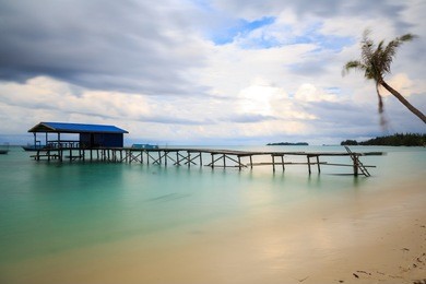 beautiful scenery landscape view of long wooden jetty and white sand beach with blue sky ocean and green ocean in mantanani island, north borneo