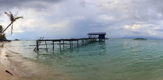 beautiful scenery landscape view of long wooden jetty and white sand beach with blue sky ocean and green ocean in mantanani island, north borneo