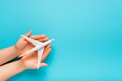 hand carefully holding model plane. airplane on blue color background. security concept