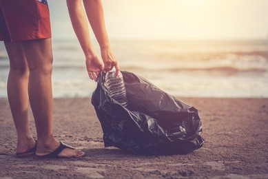 woman are collecting garbage on the beach with the backdrop of the light of the sun. / love the sea concept.