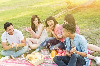 asian young man take a picnic with his friends at the park